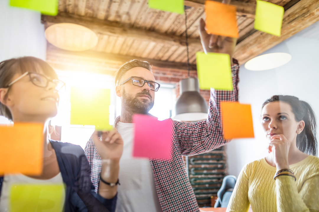 Business,People,Meeting,At,Office,And,Use,Post,It,Notes Business people meeting at office and use post it notes to share idea. Brainstorming concept. Sticky note on glass wall.